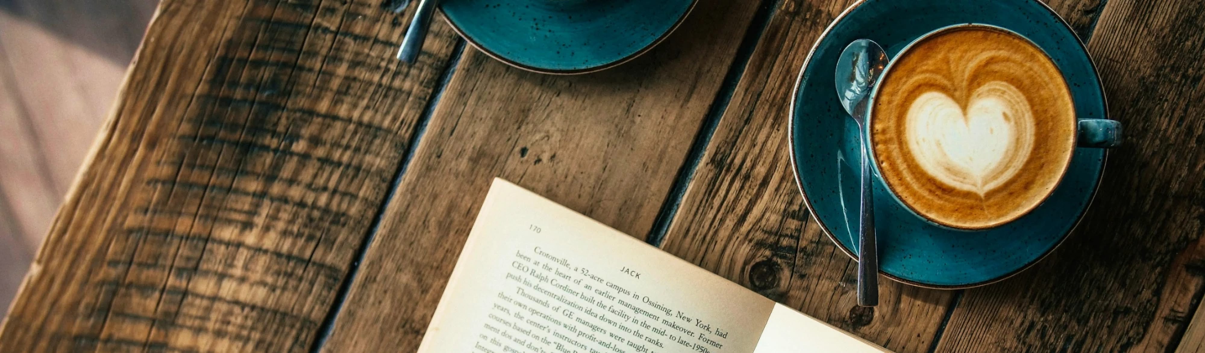 SAT project, posters for the Welcome and Transition Service: a latte in a blue cup next to an open book, on a wooden table.